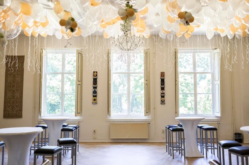 Upper hall with balloon decoration, chandelier and standing tables
