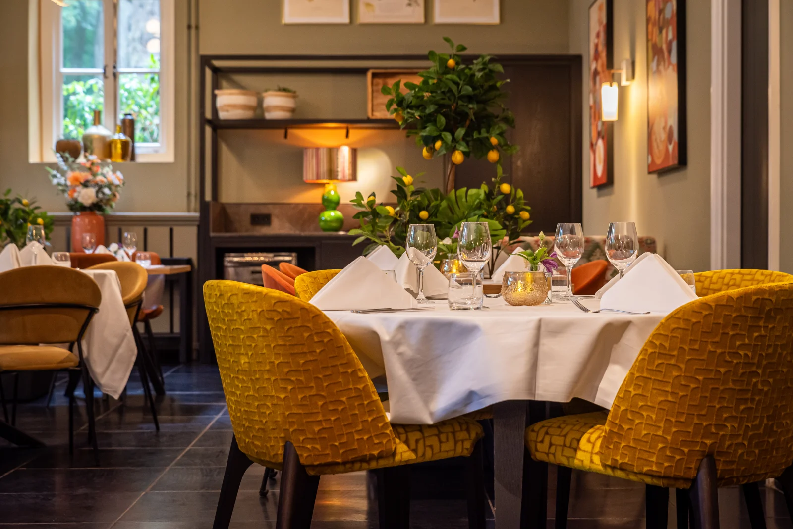 Lange gedekte tafel met kaarsen en wijnglazen in het koetshuis