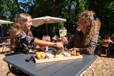 Two guests with a sharing board on the terrace among the trees
