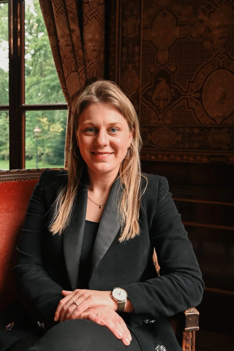 Fleur Visser zit in een leren fauteuil bij het raam in het kasteel