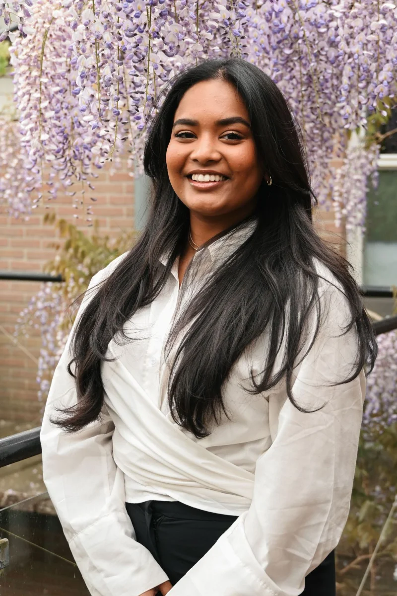 Anisha Jewlal staat onder een bloeiende blauweregen