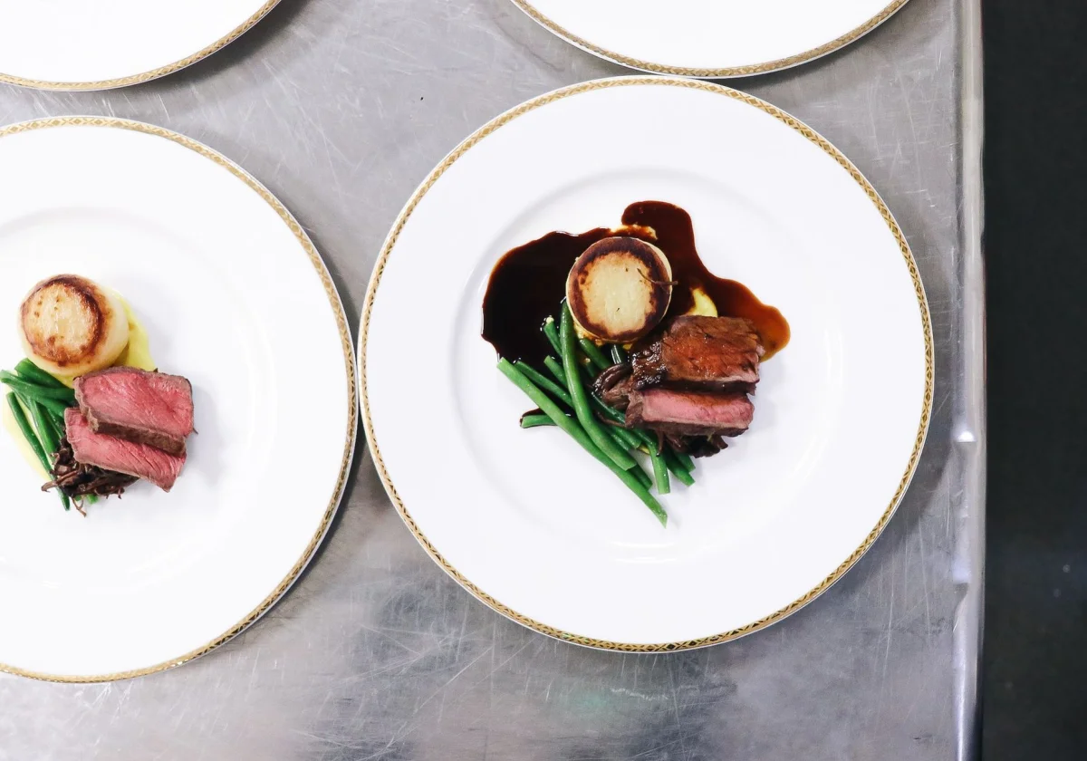 Teller mit Fleisch, Polenta und grünen Bohnen in einem hellen Restaurant